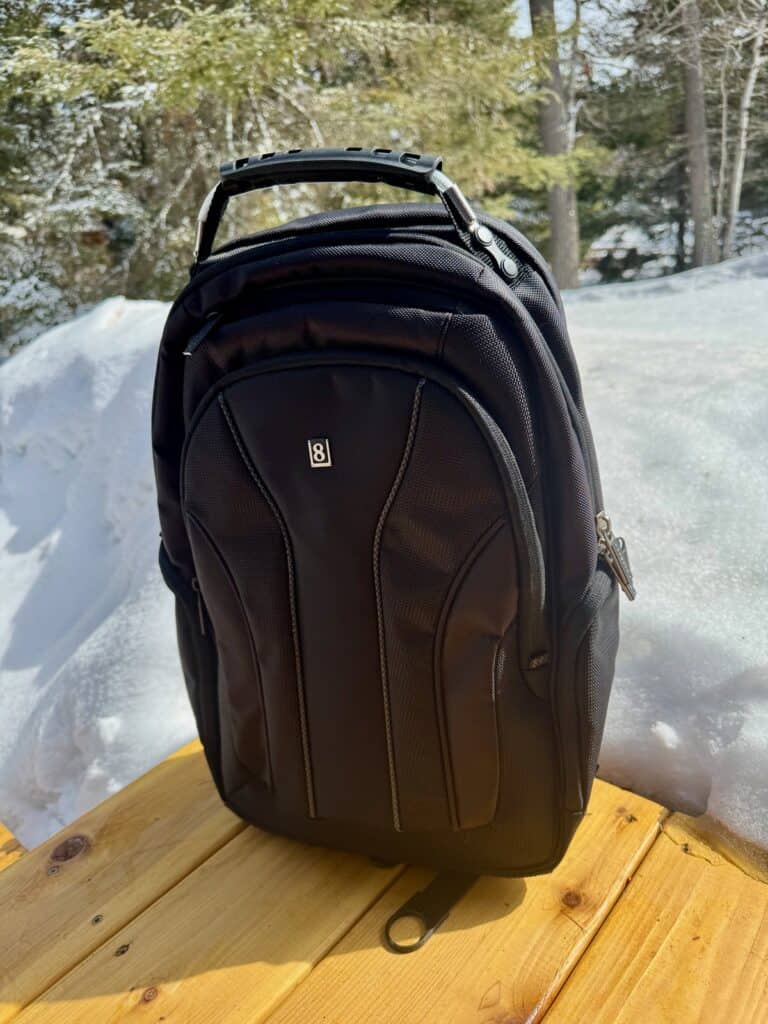 Black LEVEL8 backpack sitting on cedar decking against a snowbank