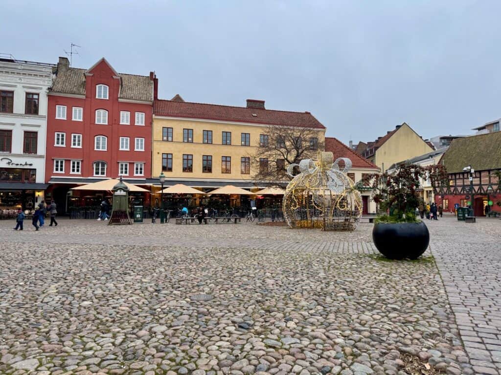 A colorful cobblestone square in Malmo Sweden old town featuring outside dining and Christmas lights