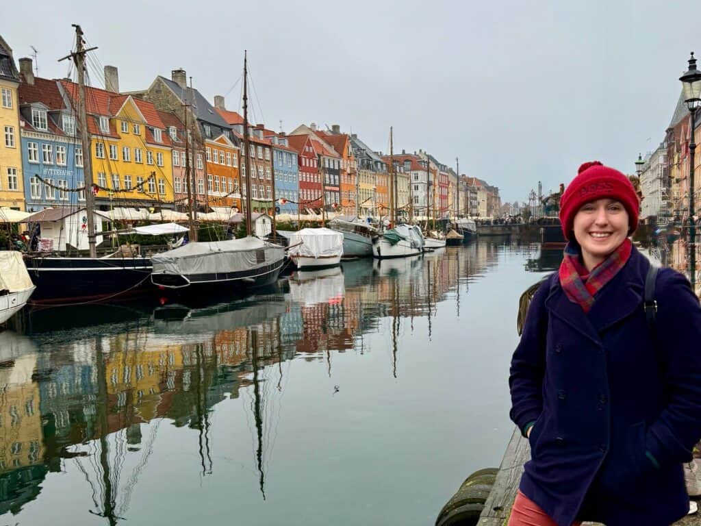 Woman poses in front of Nyhavn historic colorful buildings and waterfront in central Copenhagen
