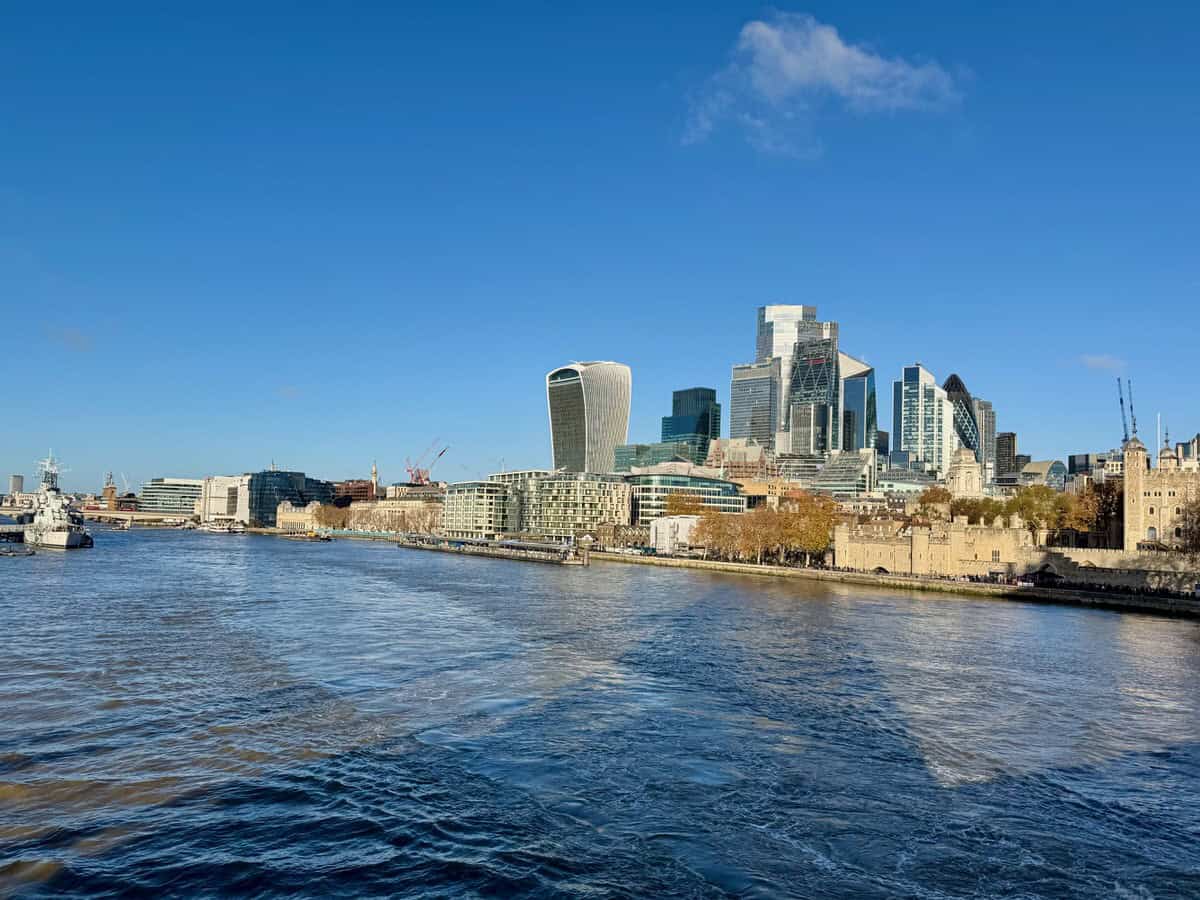 Looking across the Thames at the City of London skyscrapers and Tower of London on a sunny day.