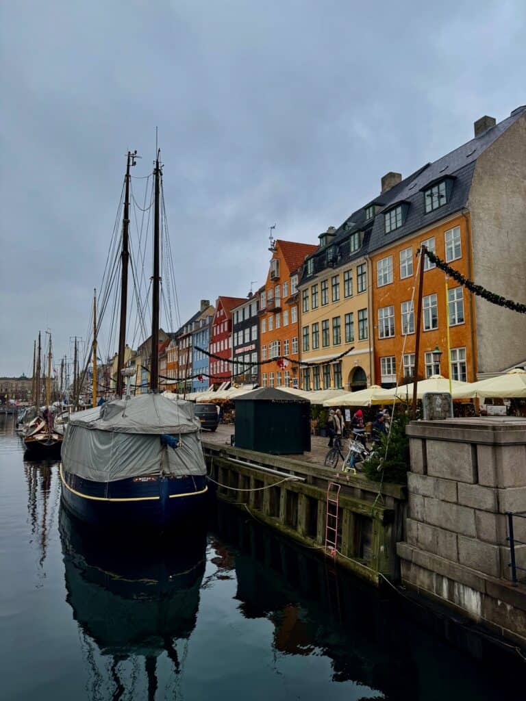Bright houses line a historic port where covered sailboats are docked