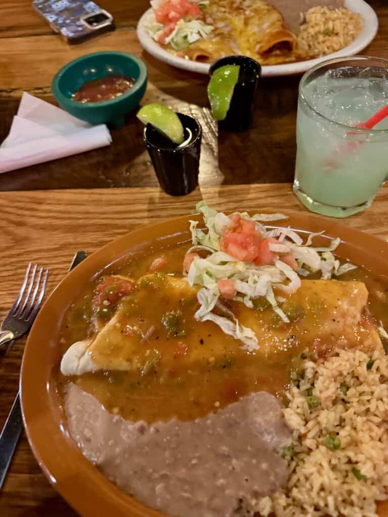 Plates of enchiladas, beans, and rice with tequila drinks at Mexican restaurant