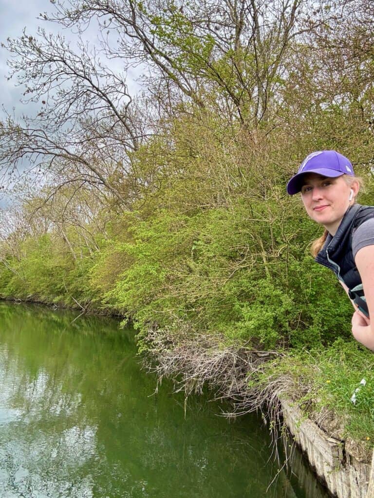 Woman walker poses in front of remote section of Thames River