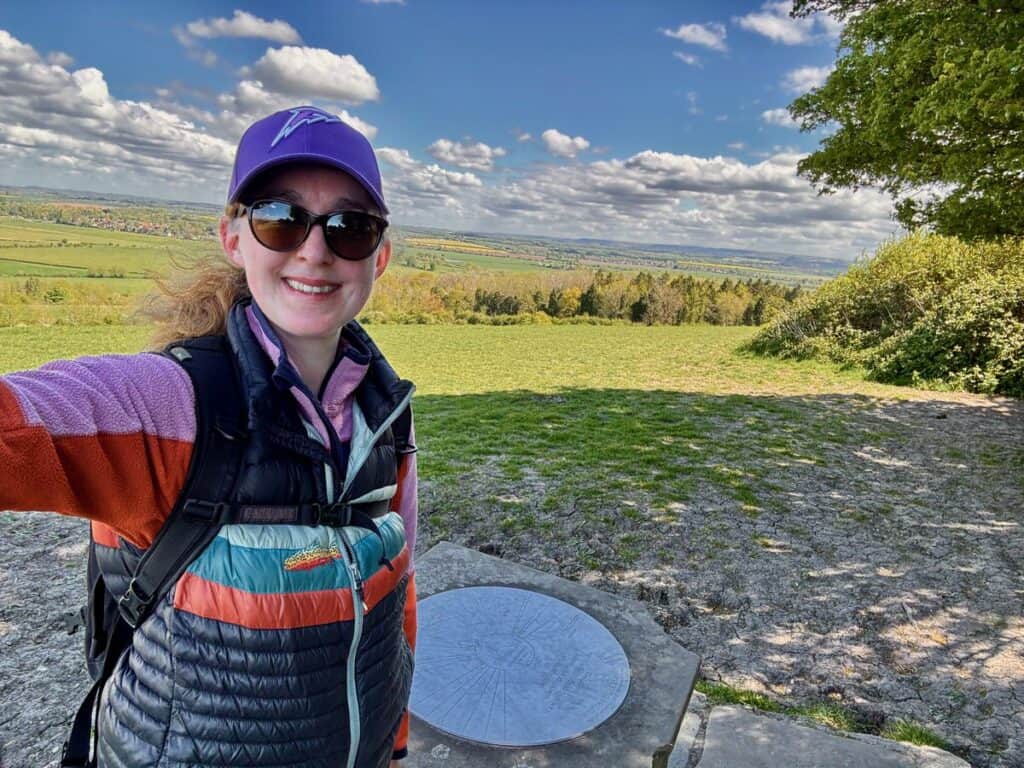 Woman poses for a selfie at the top of a hill overlooking the Thames River valley