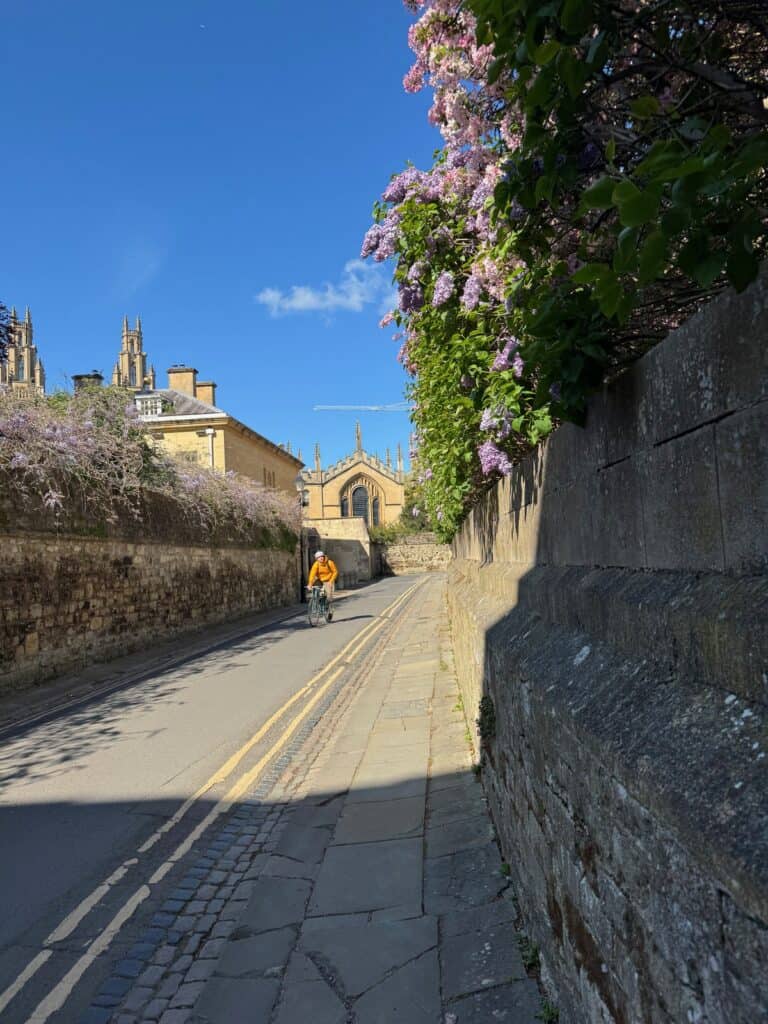 Biker on a deserted Oxford street lined with wisteria and lilacs