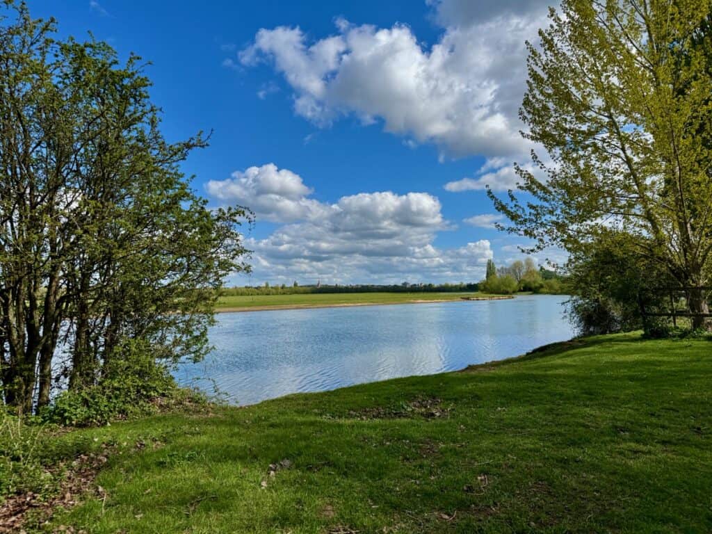 Looking across the Thames River towards a large meadow on a sunny day
